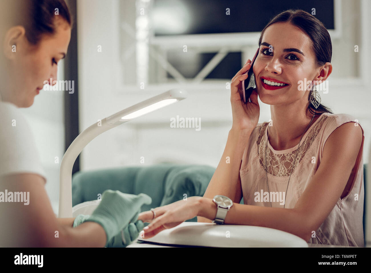 Careless smiling dark-haired client talking on the smartphone Stock Photo