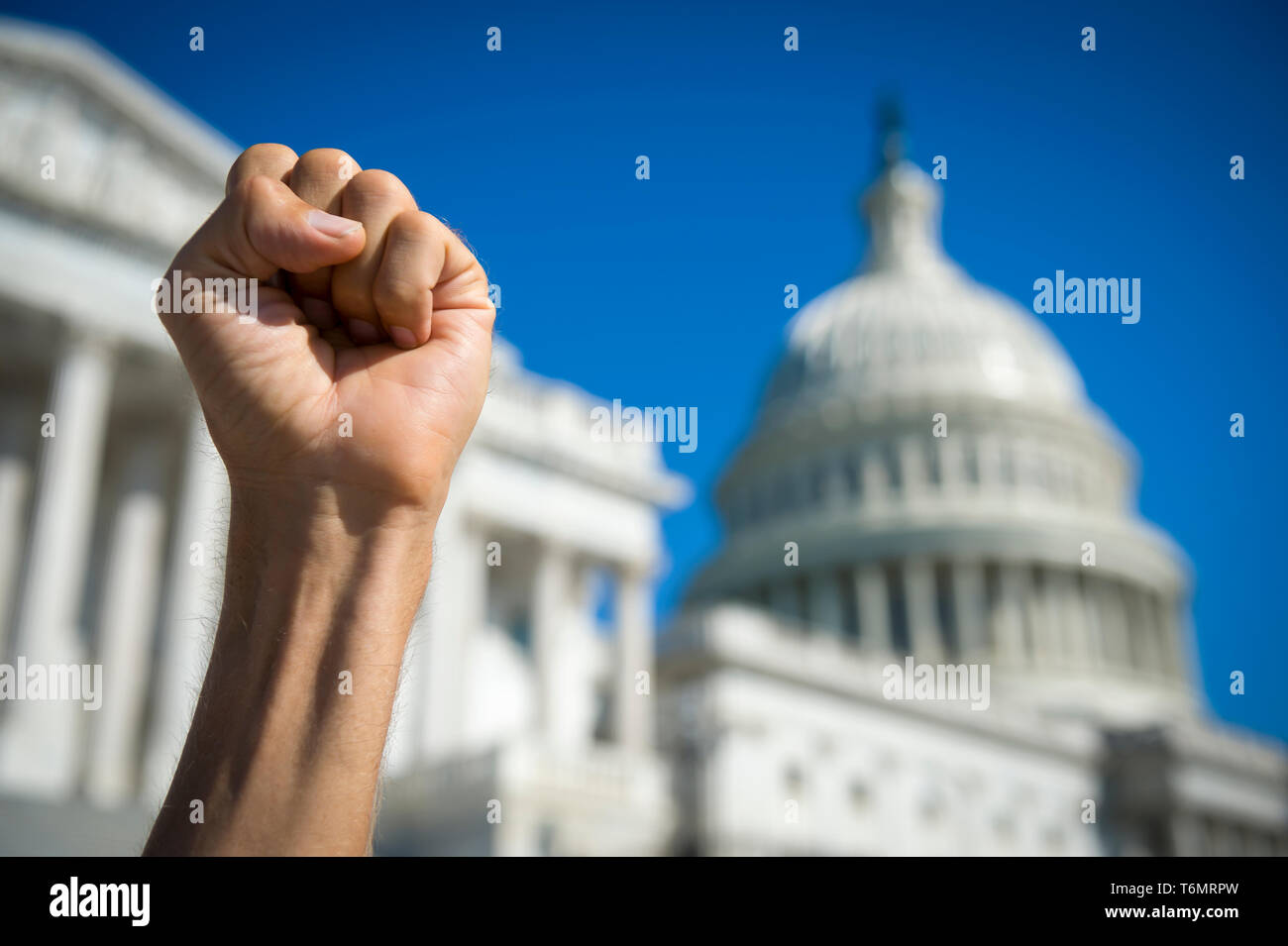 Angry fist of a protestor in the air under bright blue sky on a sunny day at Capitol Hill in Washington DC, USA Stock Photo