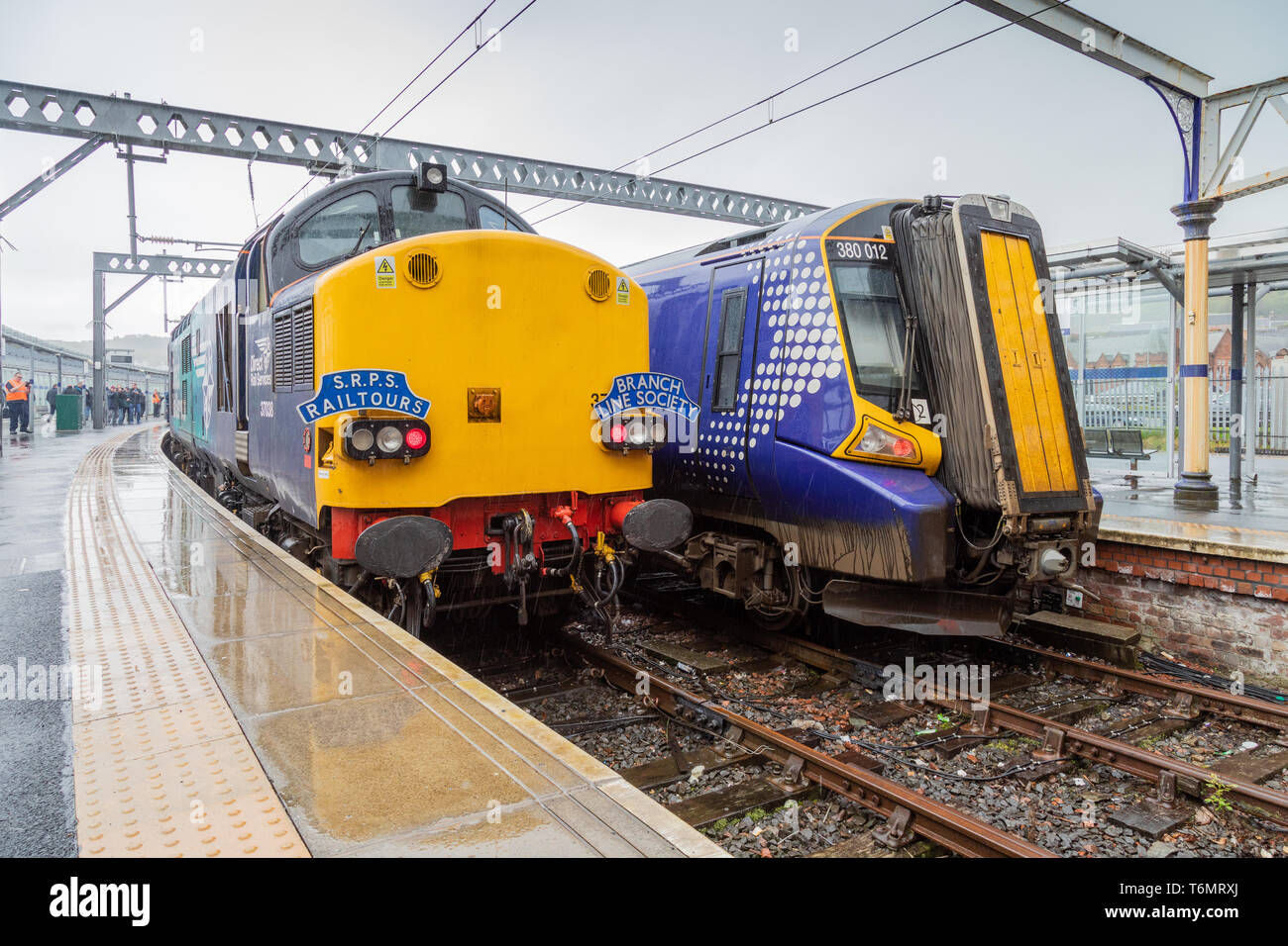 37038, a Class 37 locomotive at Gourock train station and opposite a Class 380 electric train. The Class 37 is operating an SRPS rail tour Stock Photo