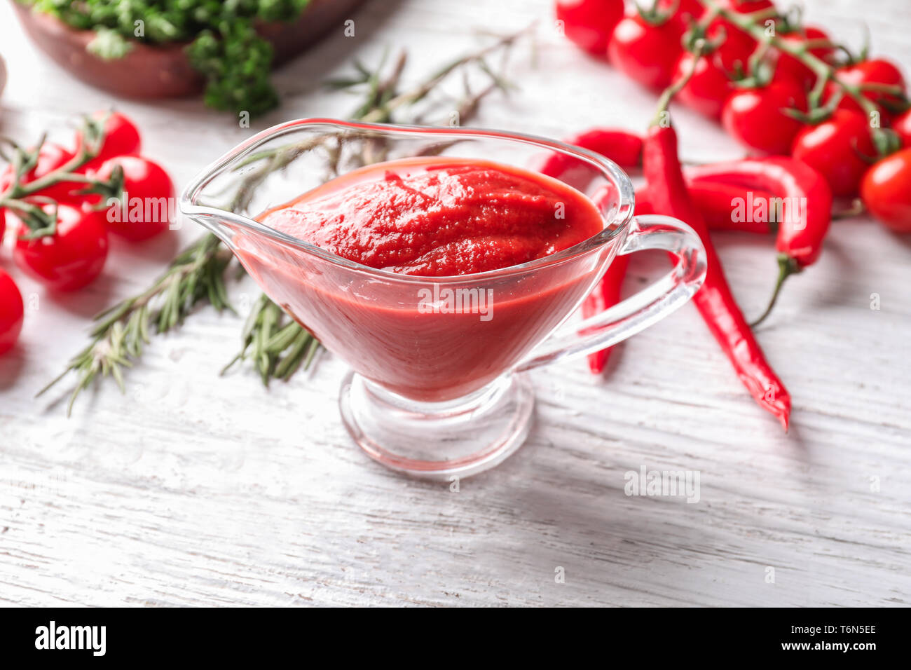 Gravy boat with delicious tomato sauce on wooden table Stock Photo