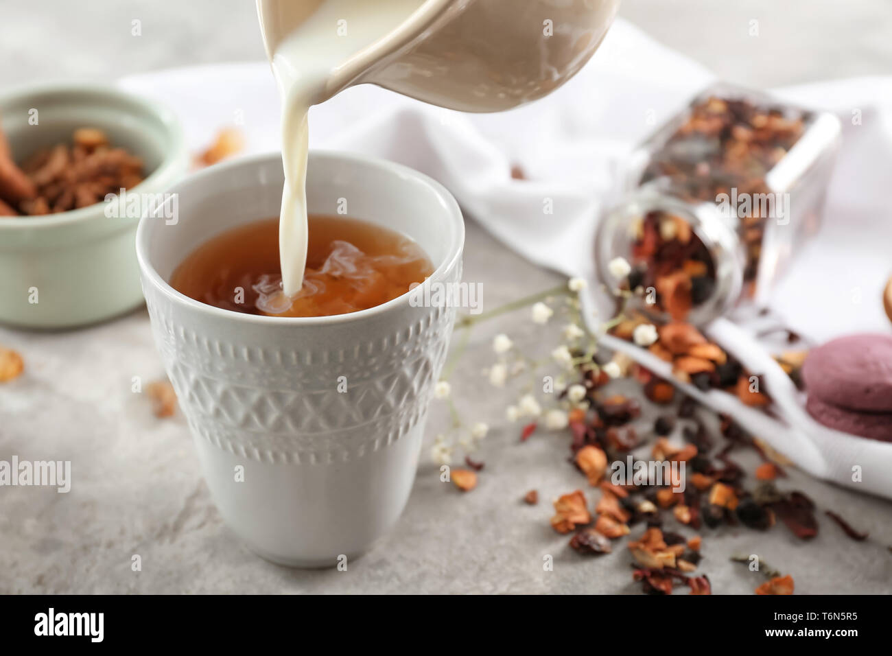 Adding milk to delicious tea on table Stock Photo Alamy