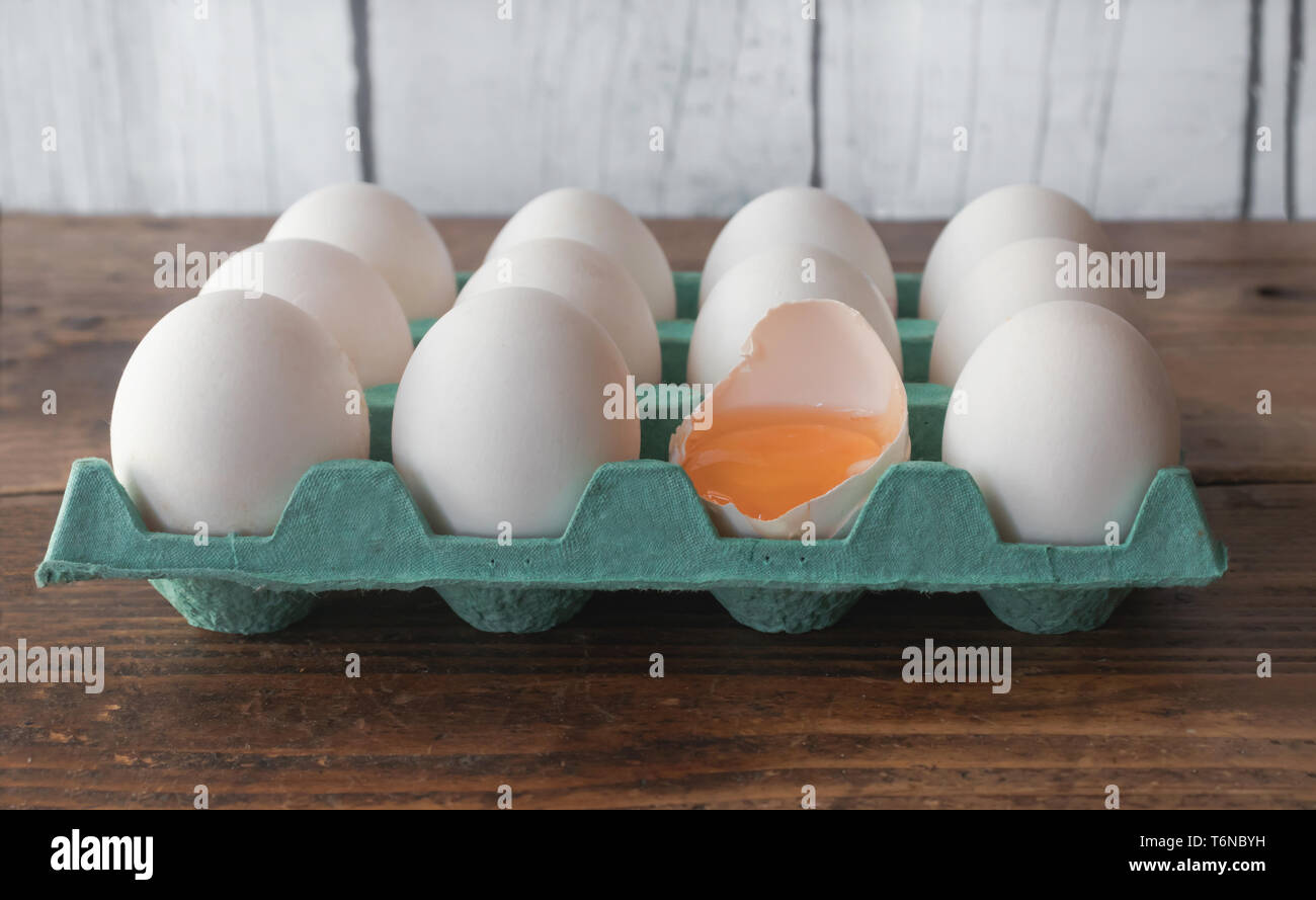 White eggs on cyan cardboard container, with an egg broken in half Stock Photo