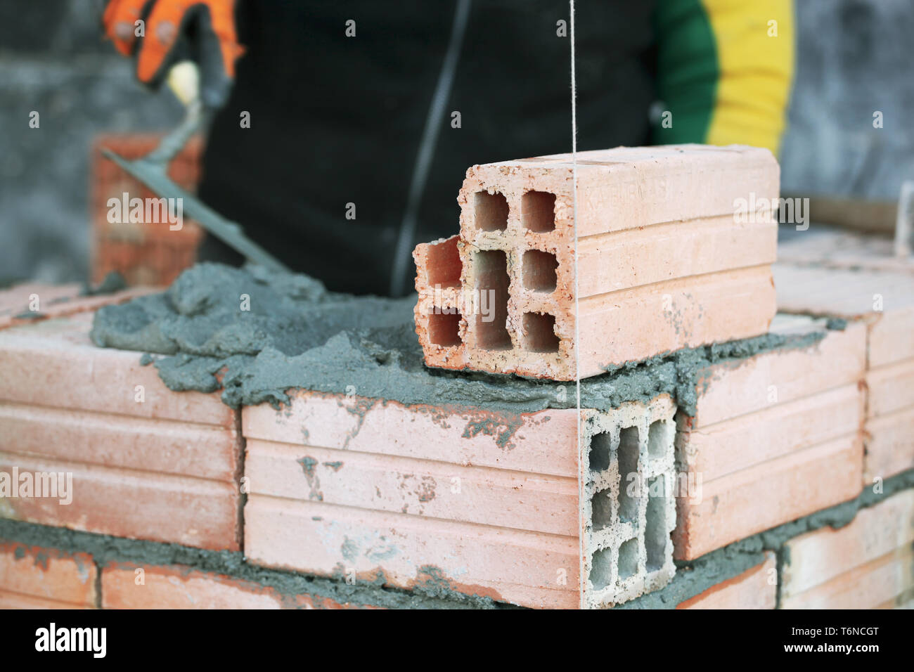 Industrial bricklayer installing bricks on construction site Stock Photo