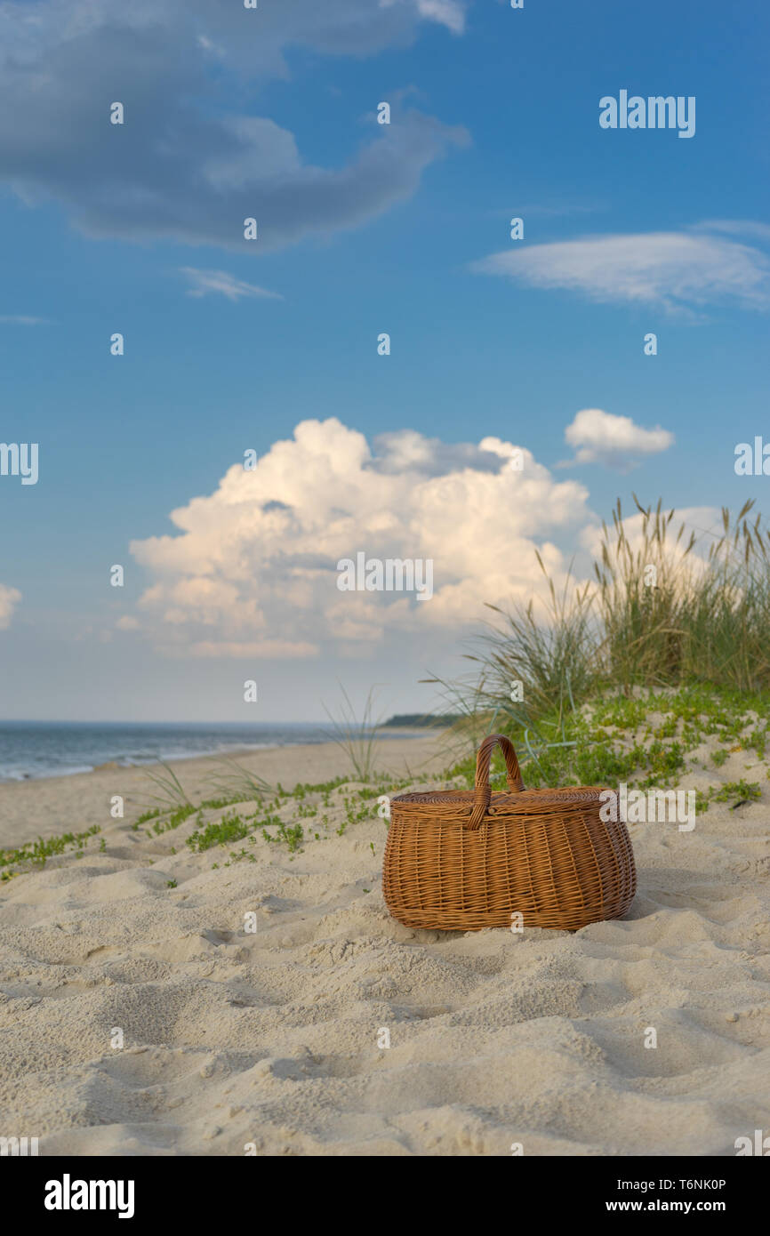 Picnic basket against scenic beach and clouds, weekend break concept Stock Photo