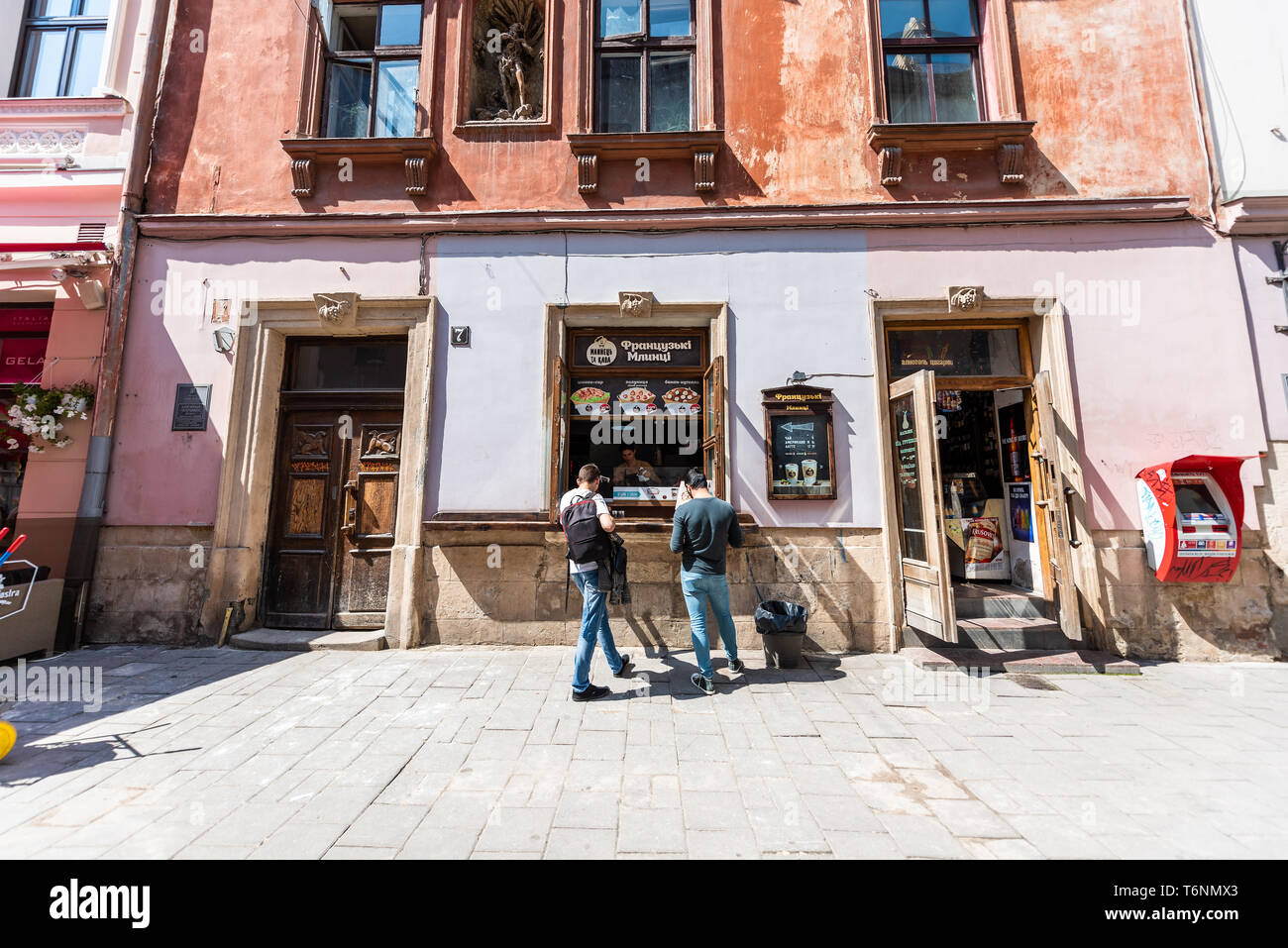 Lviv, Ukraine - August 1, 2018: Street in historic Ukrainian Polish Lvov city during day with people at counter of french crepe restaurant ordering fo Stock Photo