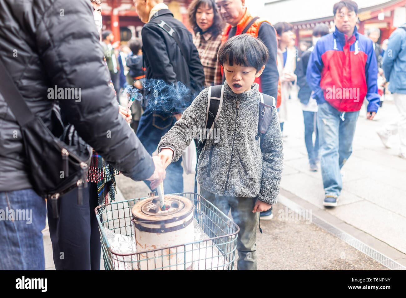 Tokyo, Japan - March 30, 2018: Asakusa district area with Sensoji temple shrine and people young boy Japanese child in awe of burning incense with smo Stock Photo
