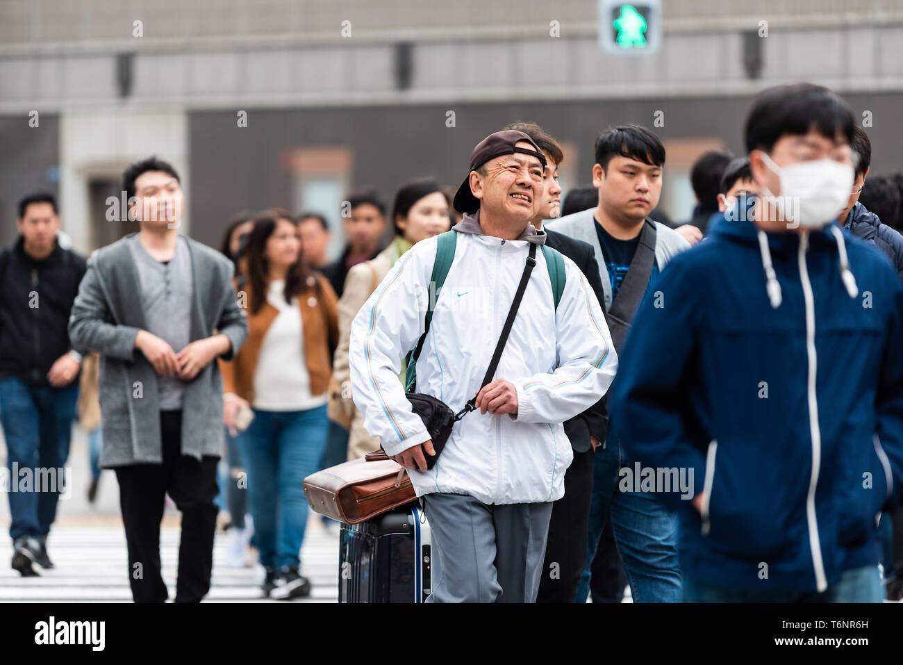 Tokyo, Japan - March 31, 2018: Ginza district with many people local Japanese walking crossing street with man in mask Stock Photo