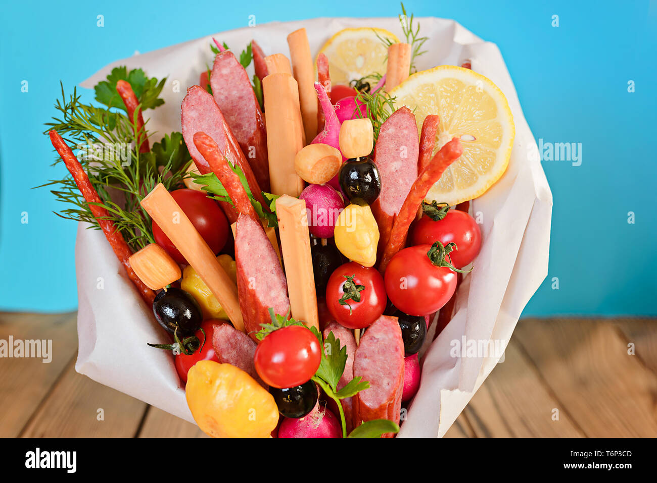 Smoked sausage, cheese, vegetables and greens, collected in a bouquet. Option gift man. On blue background. Stock Photo