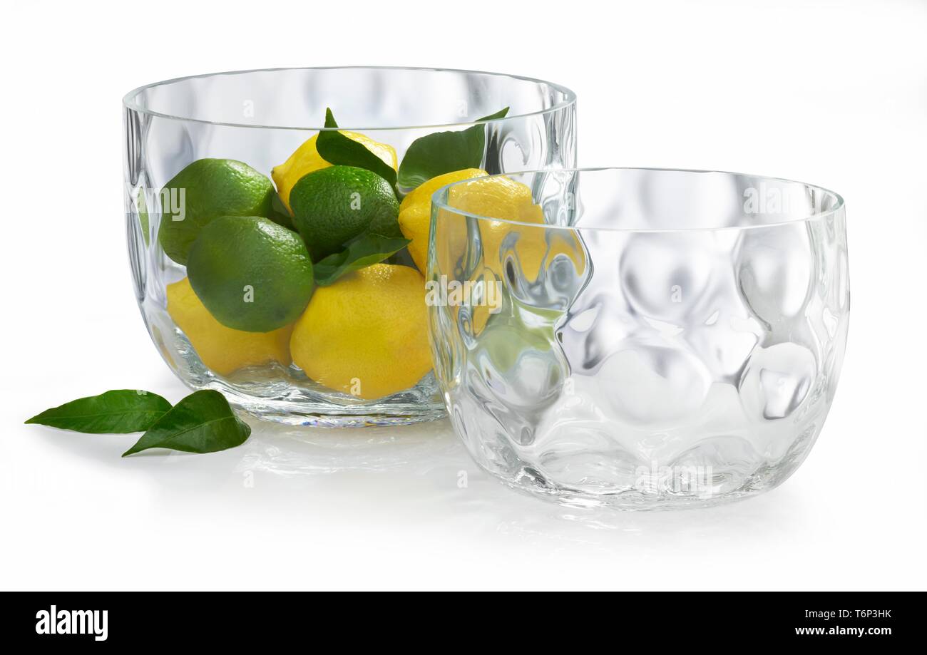 Lemons (Citrus x limon) and citrus leaves in glass bowl, Germany Stock Photo