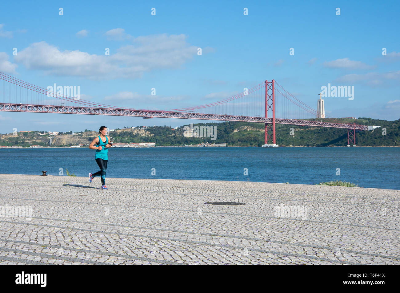 Girl jogging near Tagus River, Lisbon. Healthy life, fitness. clean air, ponte 25 de Abril bridge, suspension bridge Stock Photo