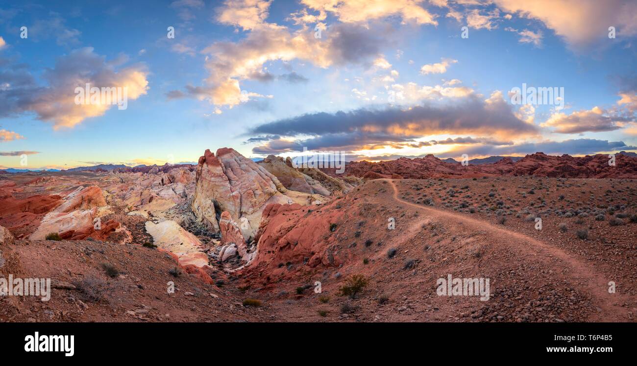 Colorful, red orange rock formations at sunset with colored clouds, hiking trail, White Dome, sandstone rocks, Valley of Fire State Park, Mojave Stock Photo