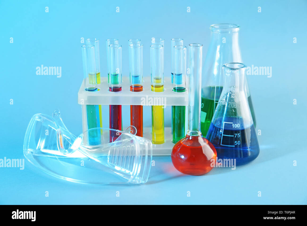 Chemical glassware with colorful samples and lab goggles on color