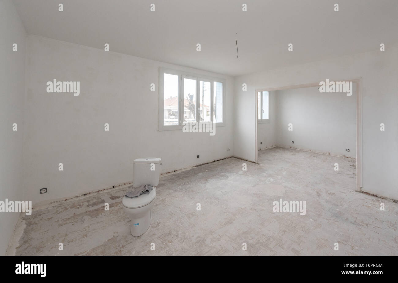 Apartment undergoing renovation: paint, floor, empty flat before refurbishment. Toilet bowl in the middle of the room Stock Photo