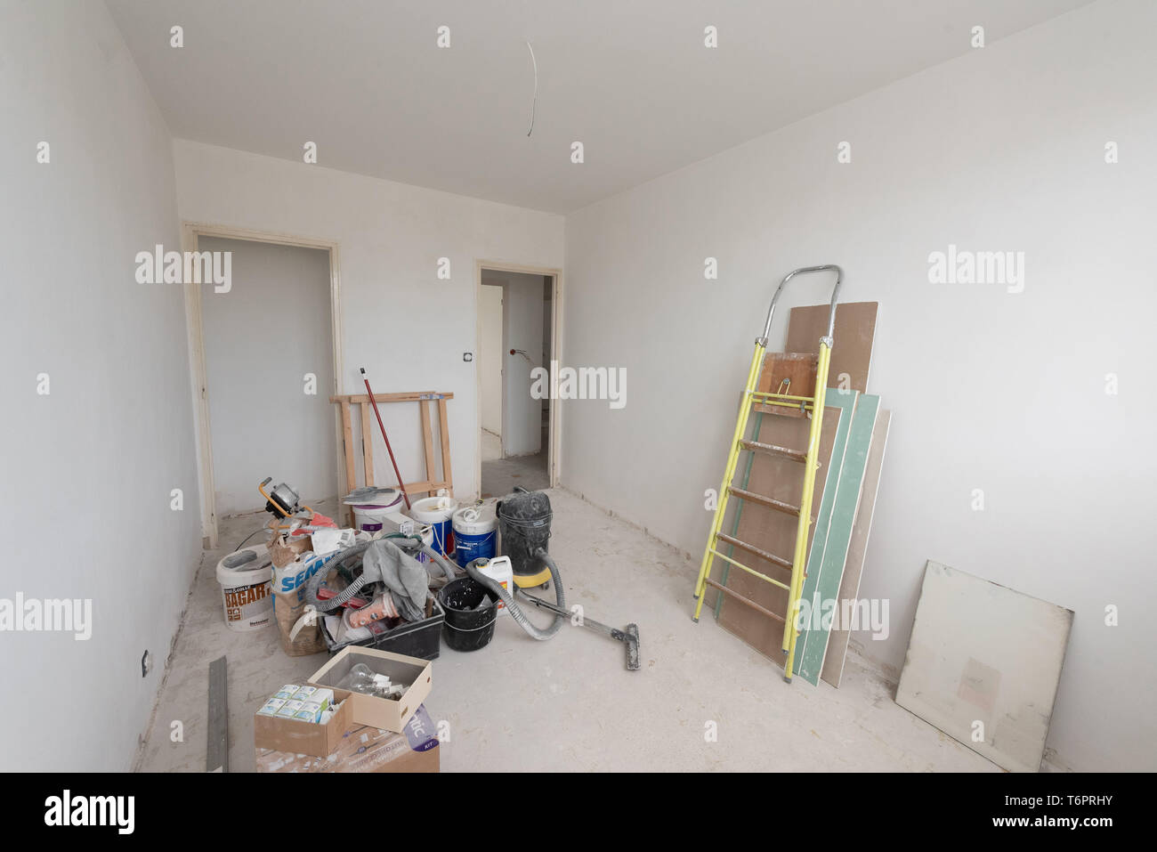 Apartment undergoing renovation: paint, floor, empty flat before refurbishment. Craftsman’s tools in a room Stock Photo