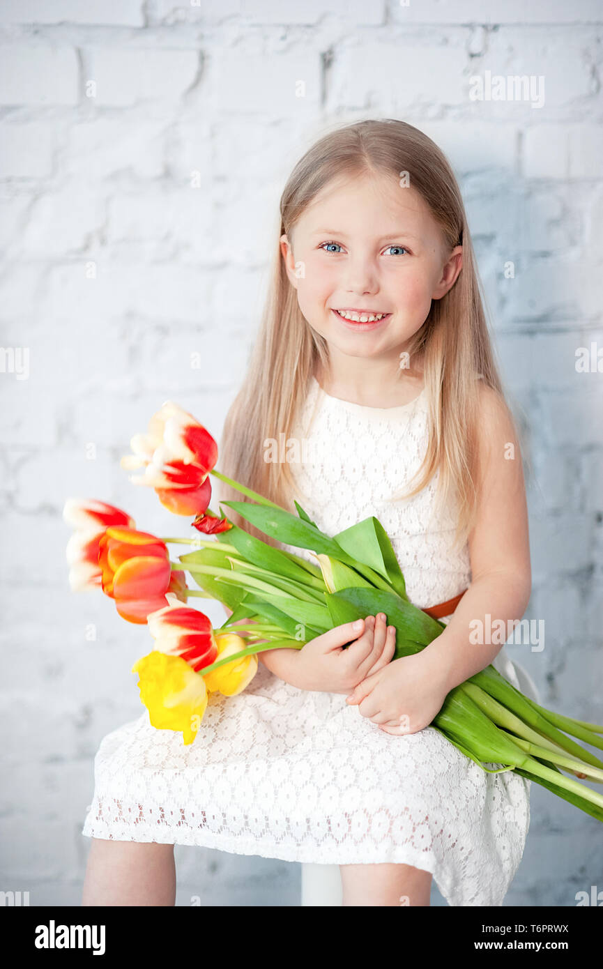 girl holding tulips in hands. Adorable smiling little girl holding flowers for her mom on mother's day. Stock Photo