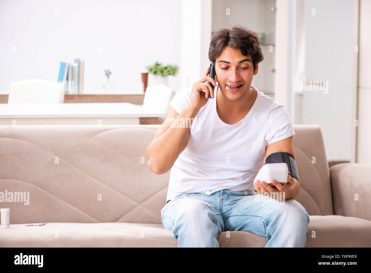 Young man measuring blood pressure at home Stock Photo - Alamy
