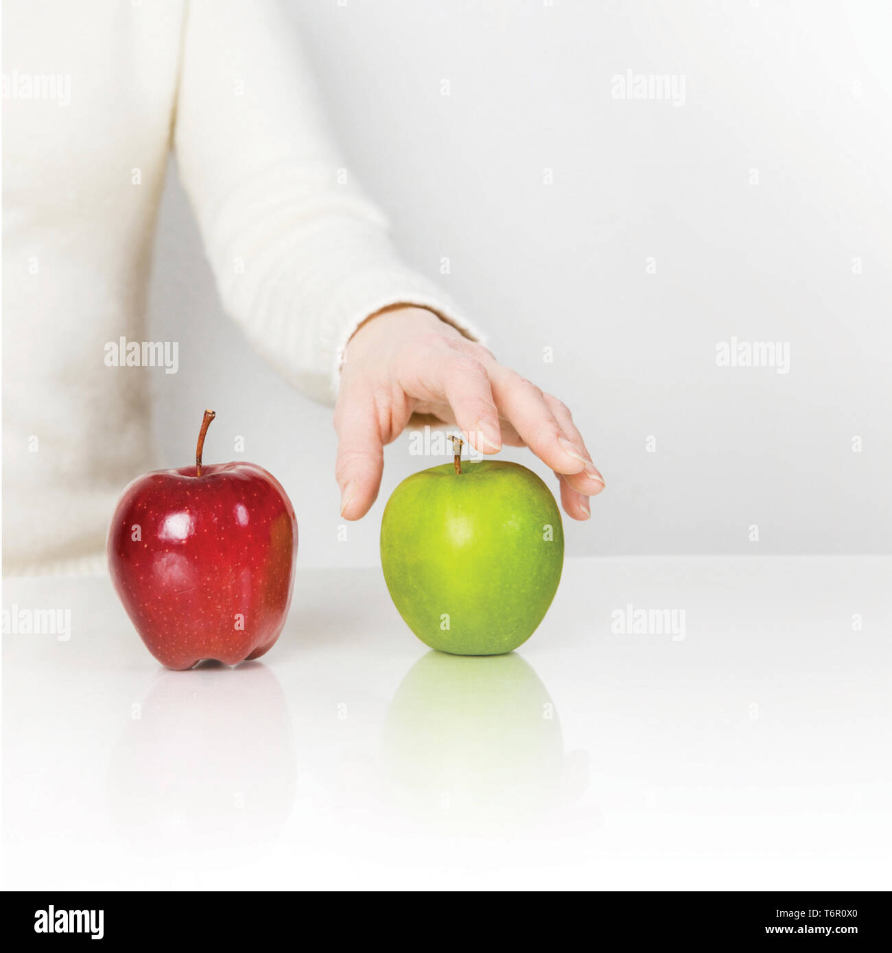 Green and Red apple on white table. Hand touching  green and red apple on the white table. isolated on white. Stock Photo