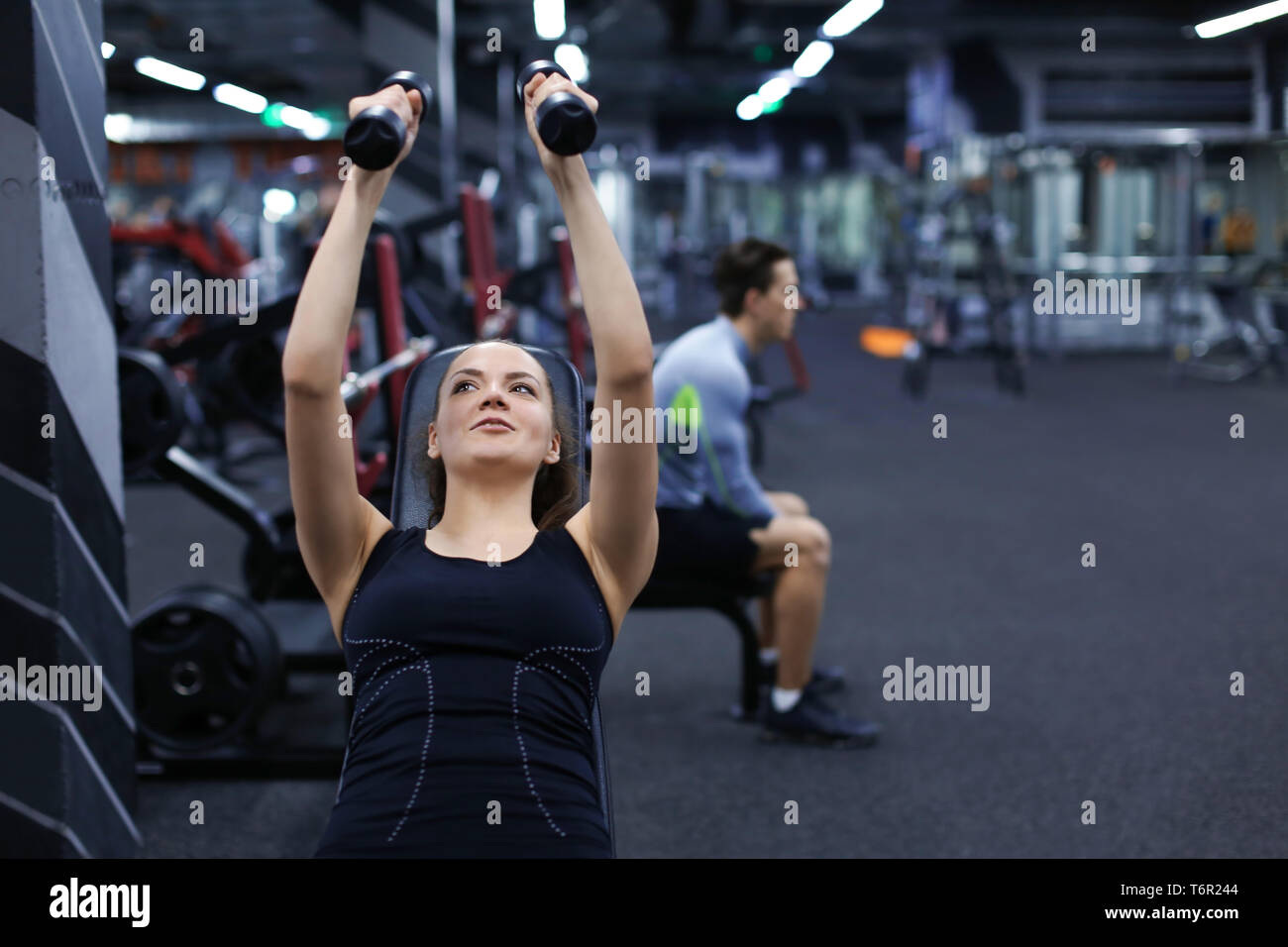 Young woman doing exercises with dumbbells in gym Stock Photo