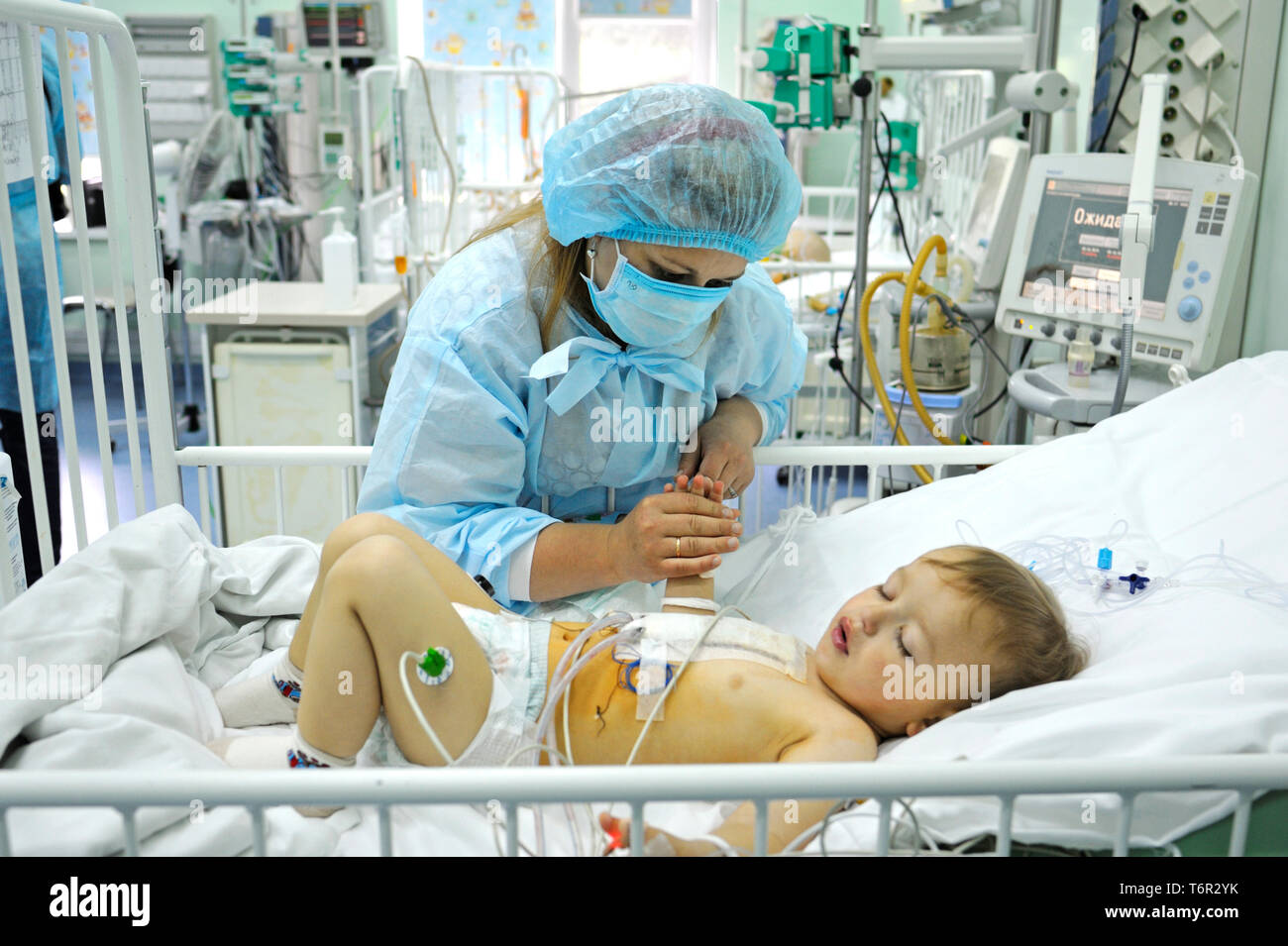 At the intensive care unit. Nurse standing near hospital bed, preparing  baby for treatment. Children’s Cardiac Center. May 18, 2018. Kiev, Uk Stock Photo