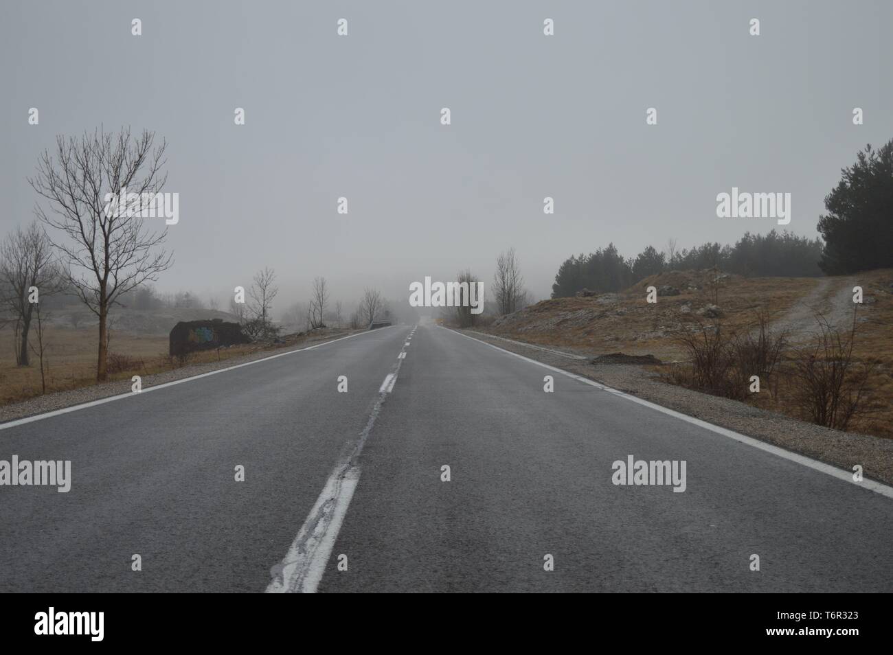 Straight mountain road disappearing in the distance on a misty day Stock Photo