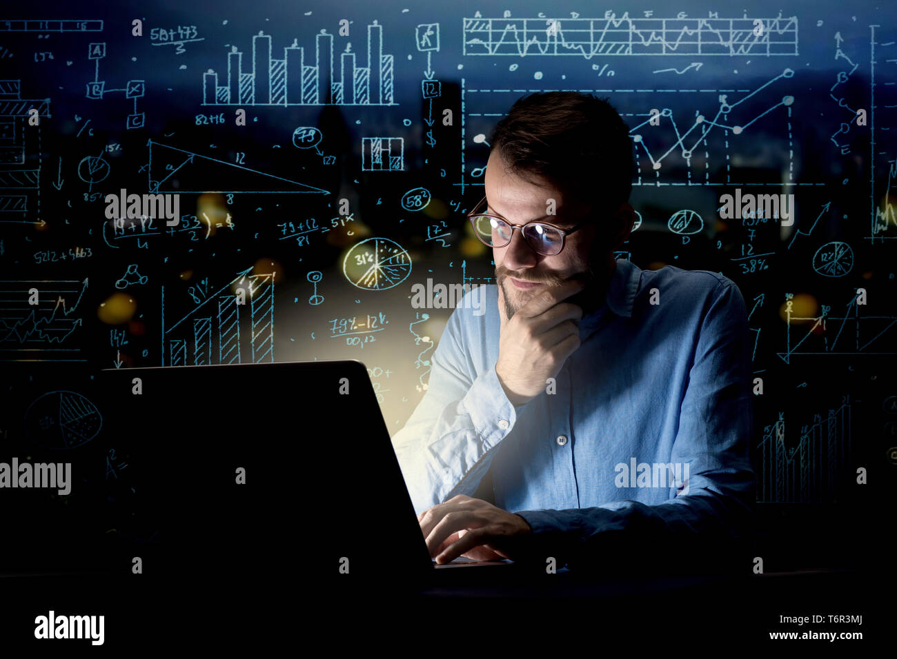 Young handsome businessman working late at night in the office with ...