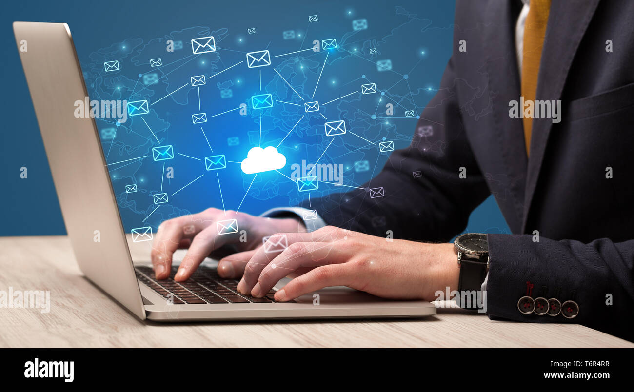 Businessman hand sending a bunch of messages on laptop with cloud Businessman hand sending a bunch of messages on laptop with cloud