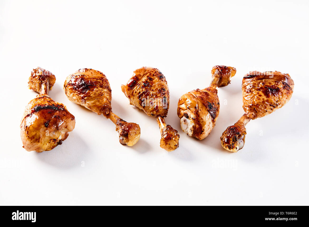 Five marinated barbecue chicken drumsticks on a white background with copy space. Stock Photo