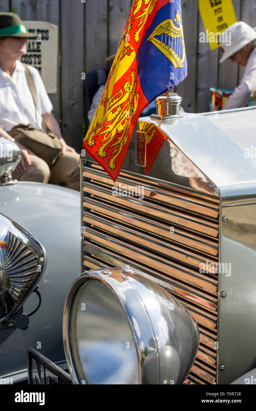 Close-up front grille of vintage, silver Rolls Royce motor car in sunshine at 1940's event, Black Country Museum, flying Queen's Royal Standard flag. Stock Photo
