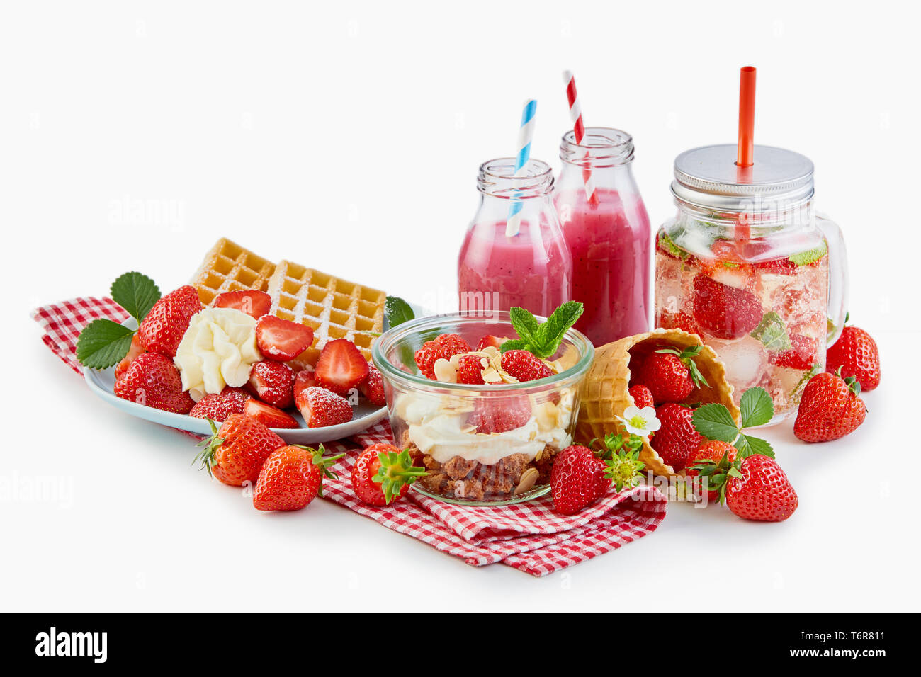 Recipes using fresh ripe strawberries over white with a waffle and cream, muesli topped with yogurt and berries, smoothies, infused water and whole fr Stock Photo