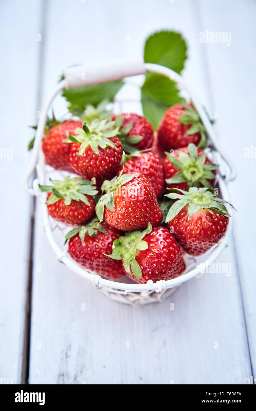 High-angle close-up view of a rustic basket full of fresh and nutritious strawberries on a wooden table outdoors with copy space Stock Photo
