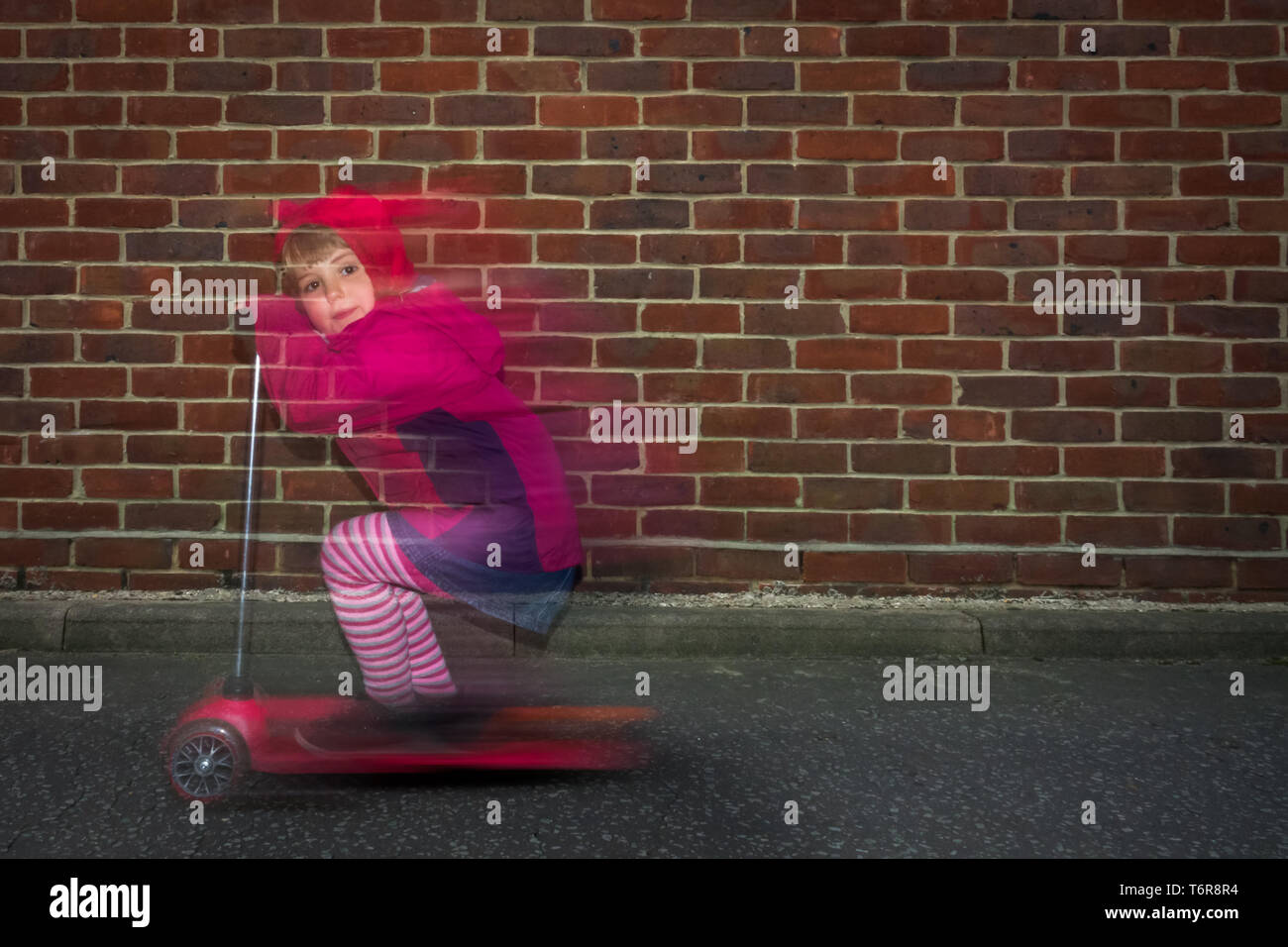 Little girl riding fast on her scooter Stock Photo - Alamy