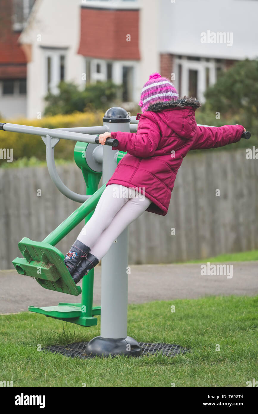 A young girl uses outdoor exercise equipment to exercise in a park on a  sunny day Stock Photo - Alamy