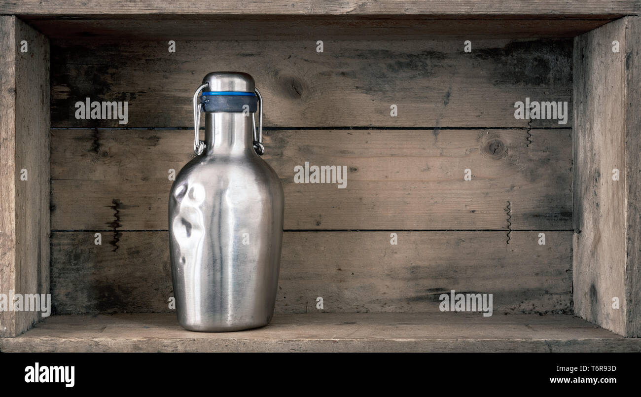 old dented metal bottle on wooden background Stock Photo