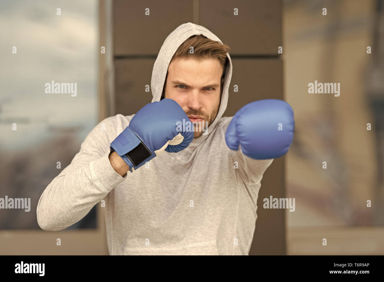 Strength and motivation. Sportsman concentrated training boxing gloves.  Athlete concentrated face with sport gloves practice fighting skills urban  background. Boxer handsome strict coach practicing Stock Photo - Alamy