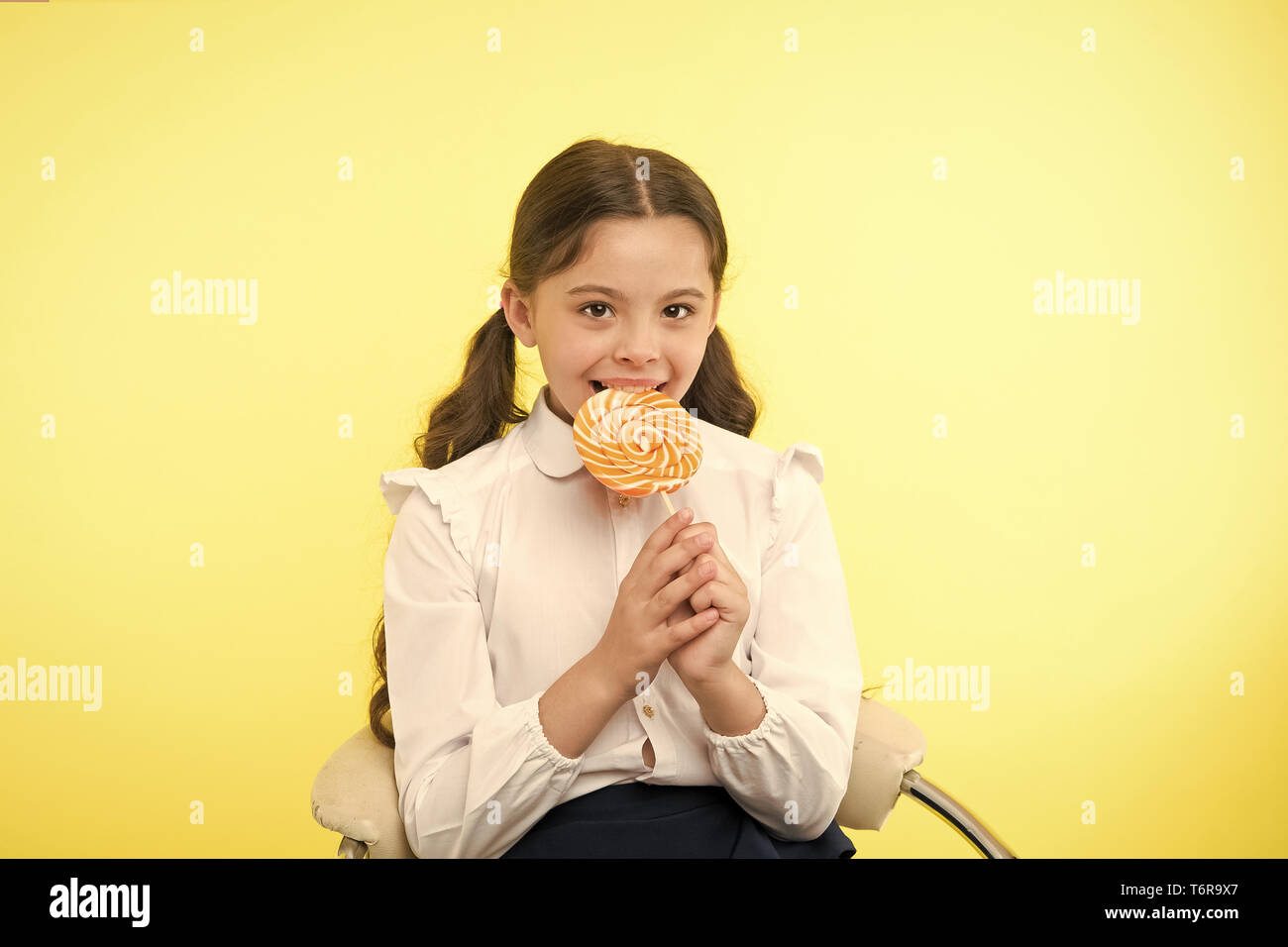 lollipop child. child eating lollipop in yellow studio. lollipop child