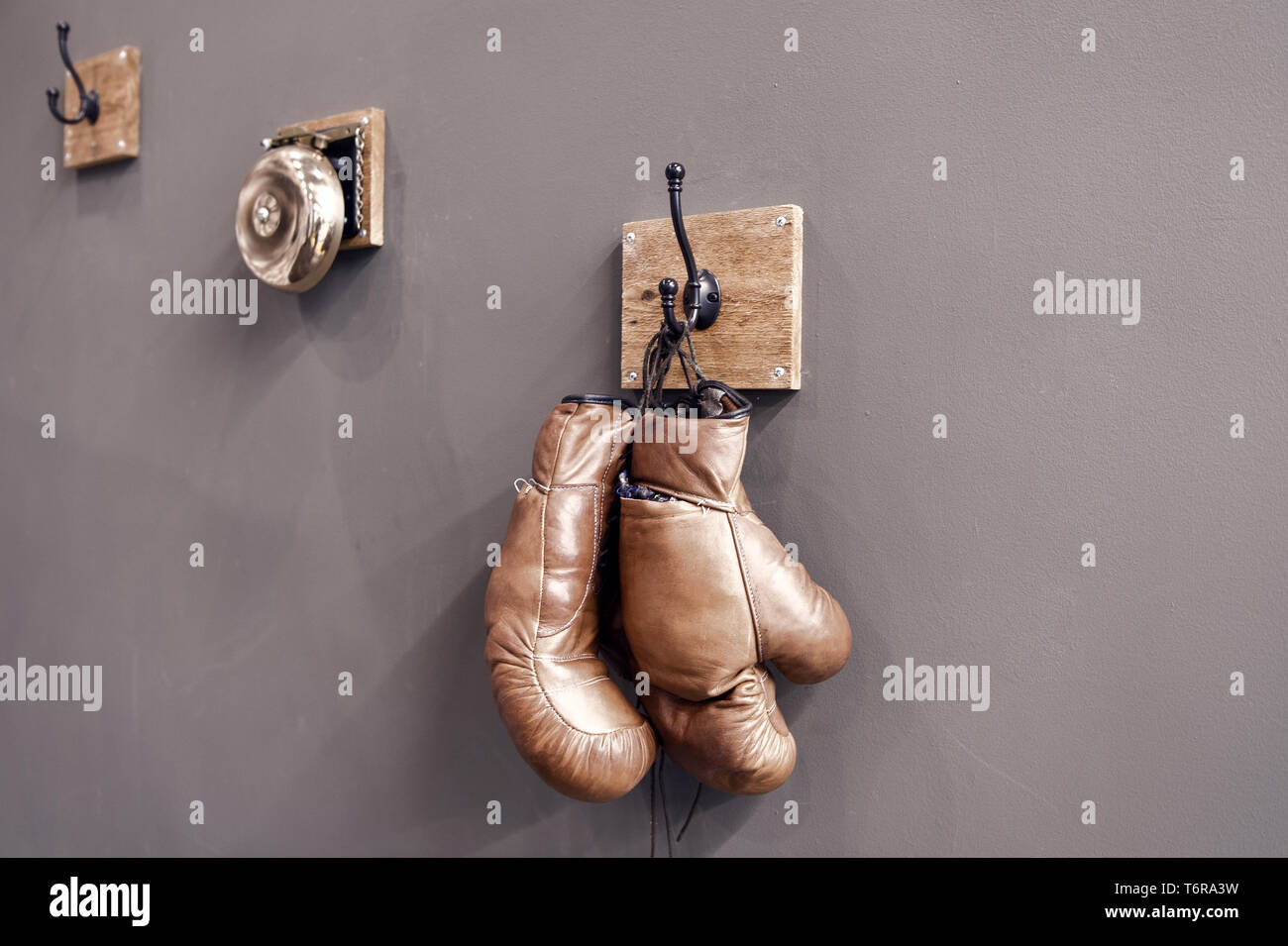 Boxing school. Final sparring. Vintage boxing gloves hang on hook wall background. Boxing gloves and ring bell. Boxing career famous sportsman. Museum of box sport. Box exhibition retro attributes. Stock Photo