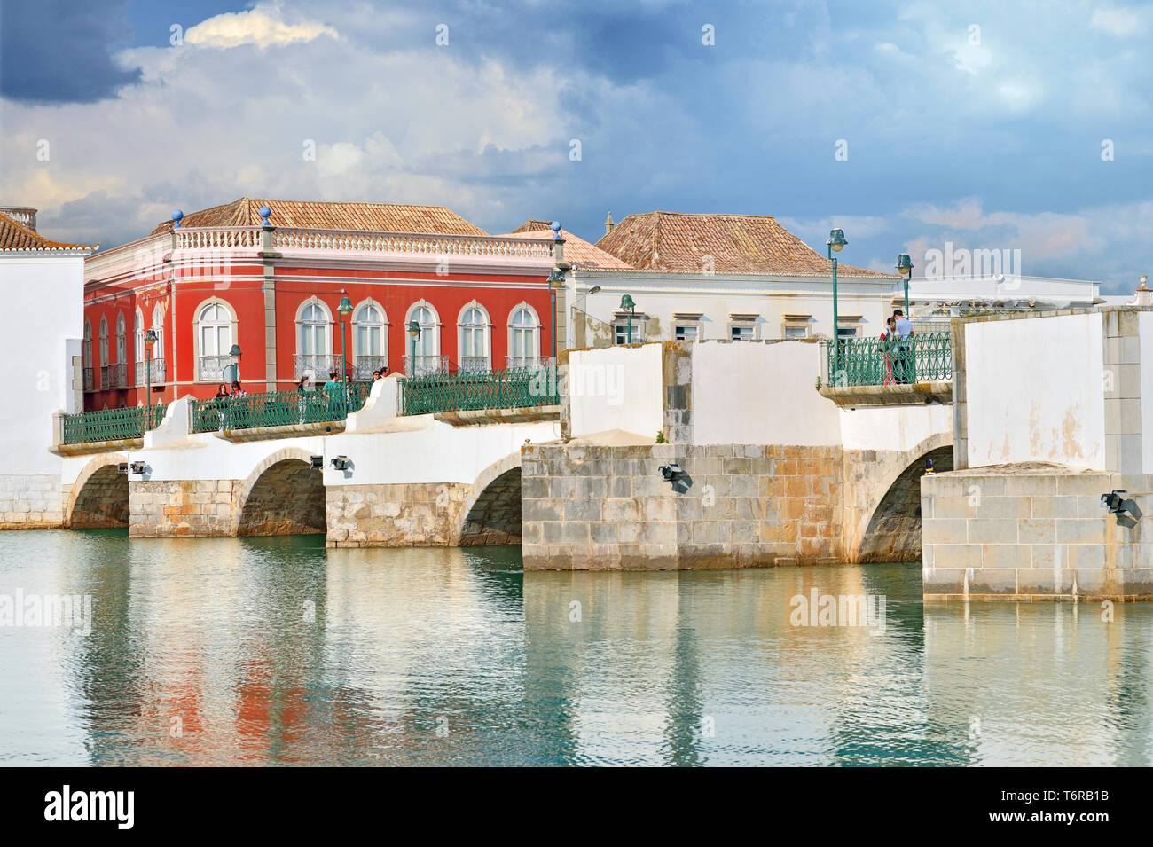 Side view of Romanesque bridge over calm river and historic buildings Stock Photo