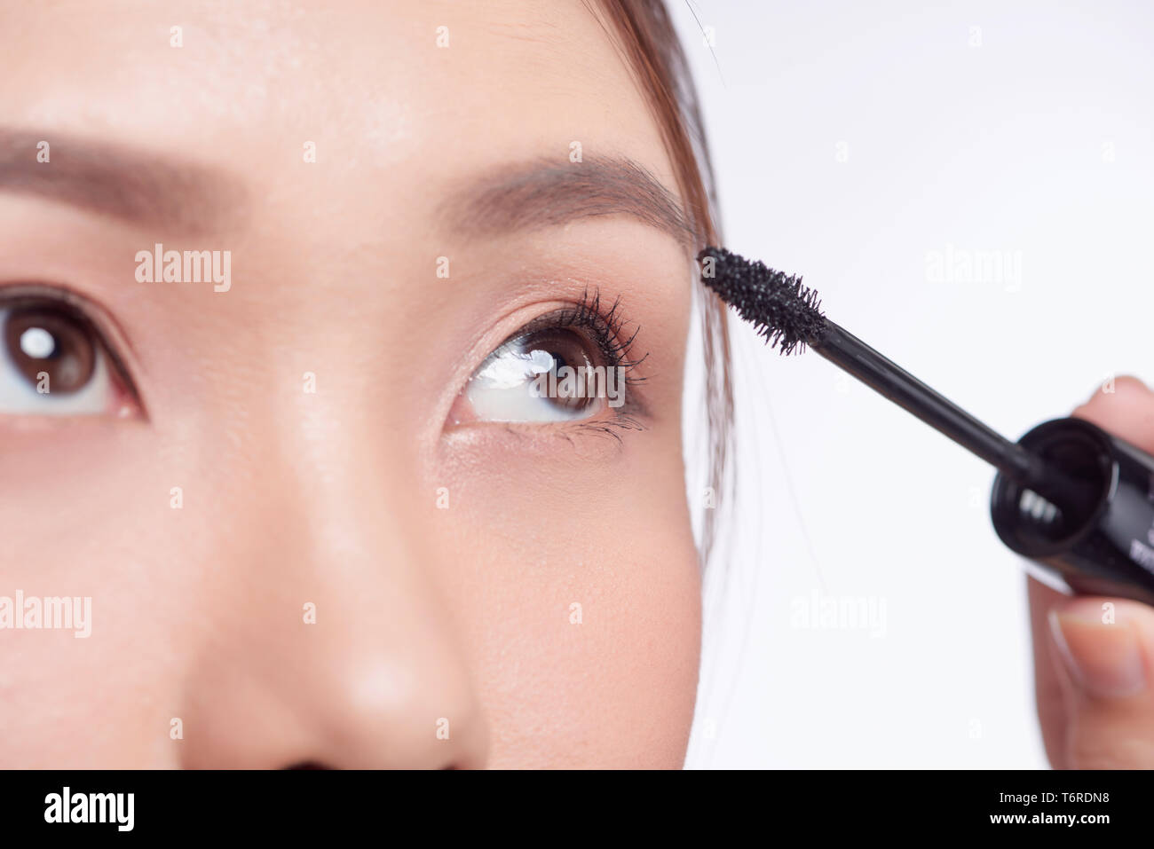 Mascara woman putting makeup on eyes. Asian female model face closeup