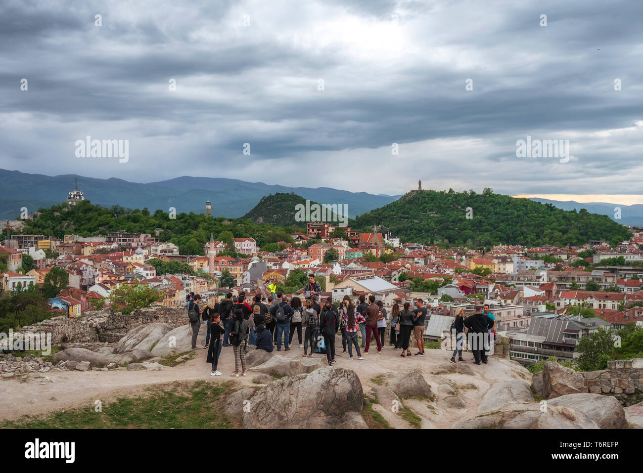 Tourists watching sunset during warm spring day from one of the hills in the city Stock Photo