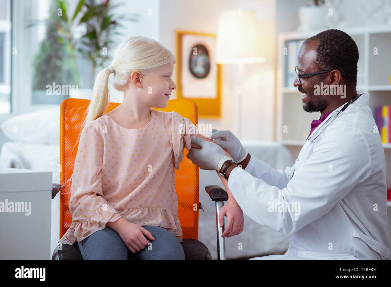 Pediatrician smiling while making injection for schoolgirl Stock Photo
