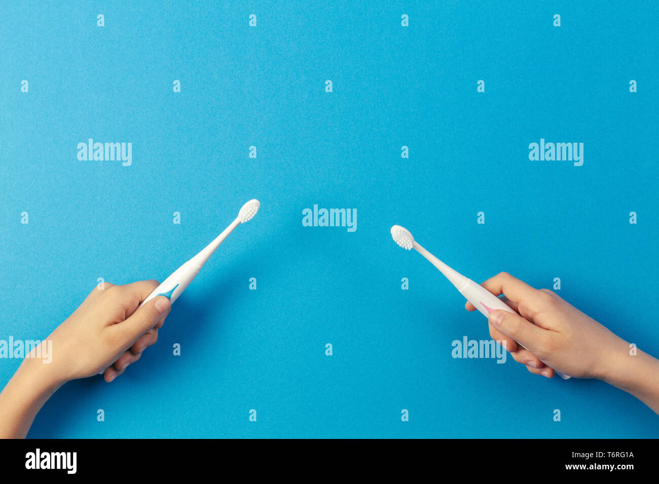 Kid hands with electric toothbrushes on blue background Stock Photo