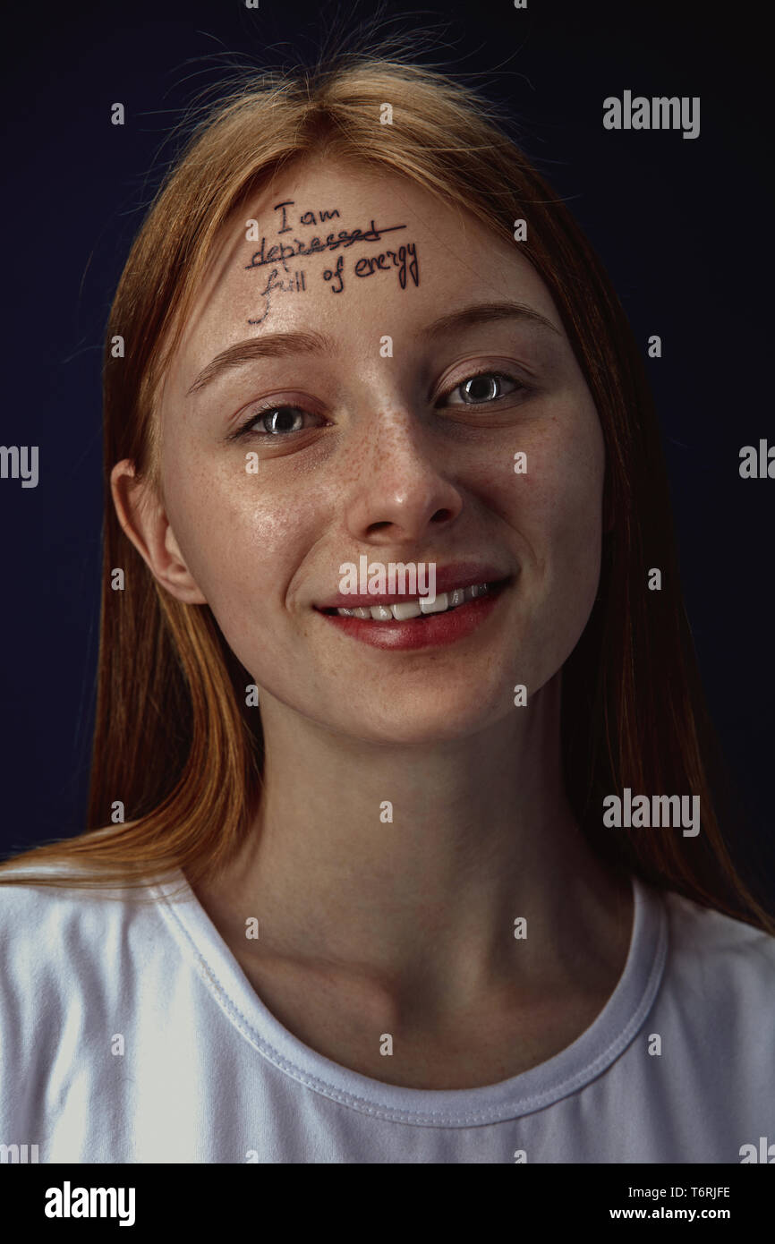 Portrait of young woman overcoming mental health problems. Tattoo on the forehead with the words I'm depressed-full of energy. Concept of psycological rehabilitation, return to healthy lifestyle. Stock Photo