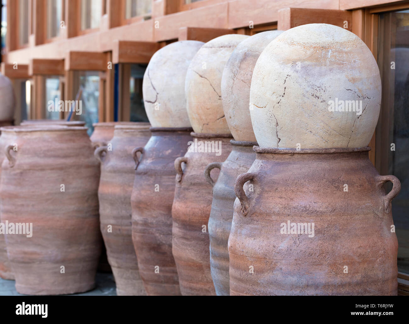 Large clay brown pots are covered with stone eggs and stand in a row