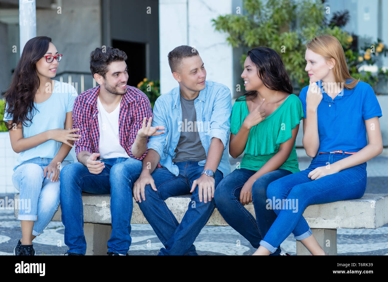 Young adult man telling story to friends outdoor in the summer in the city Stock Photo