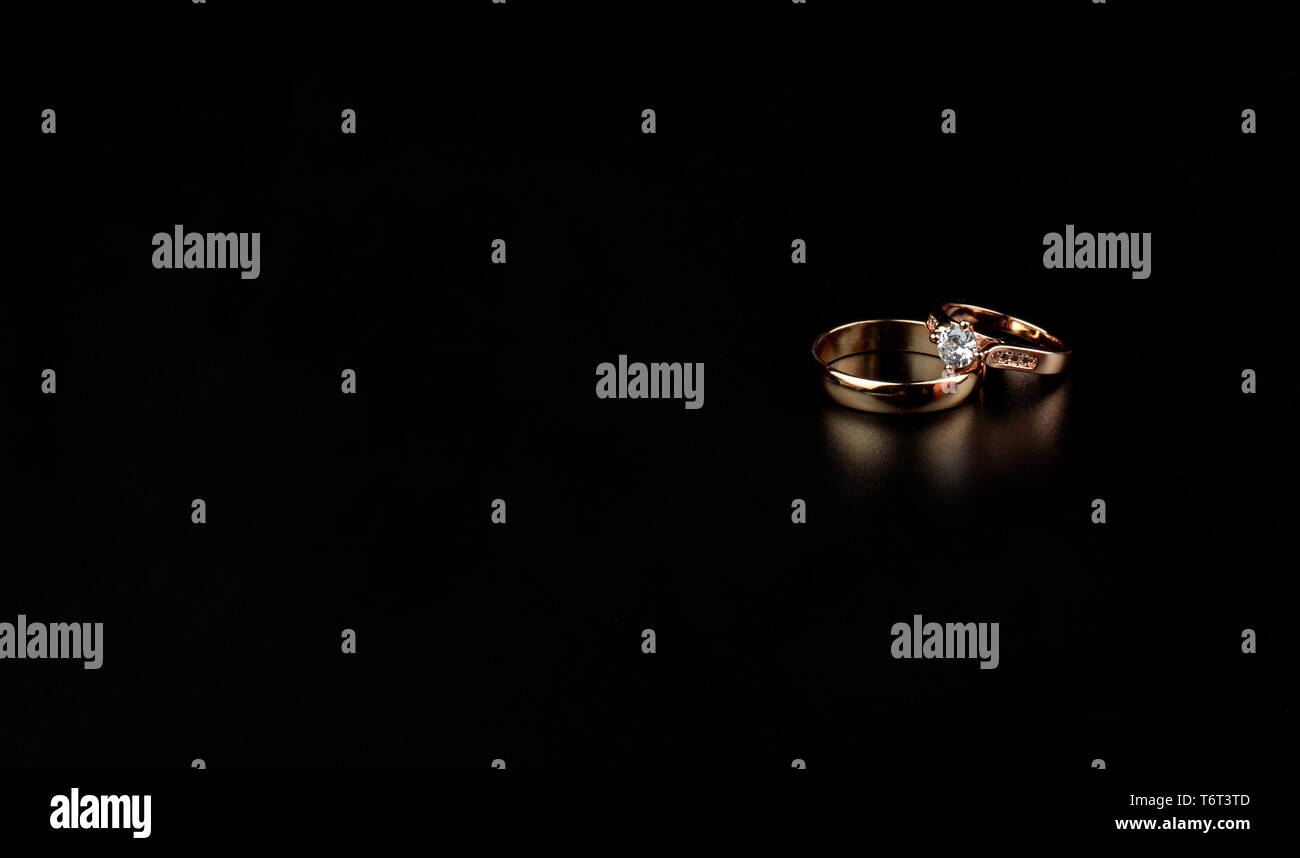 gold wedding rings with a diamond for newlyweds on an isolated black ...