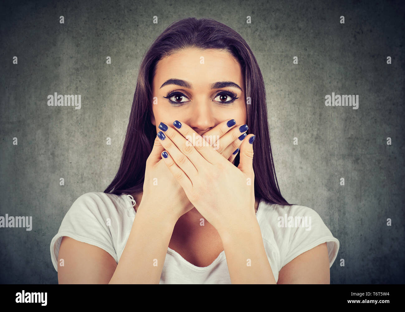 Scared woman covers her mouth to keep it quiet isolated on gray ...