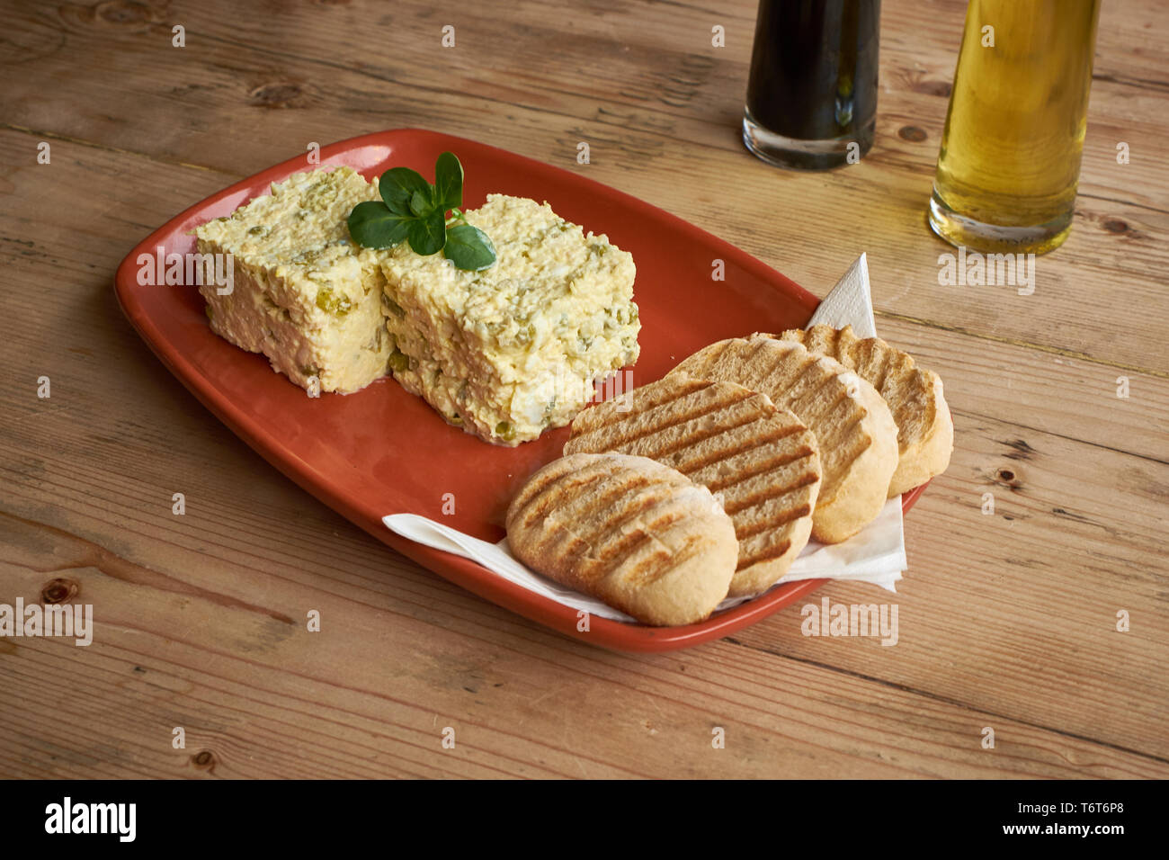 Olivieh Salad on a red plate and wooden table Stock Photo