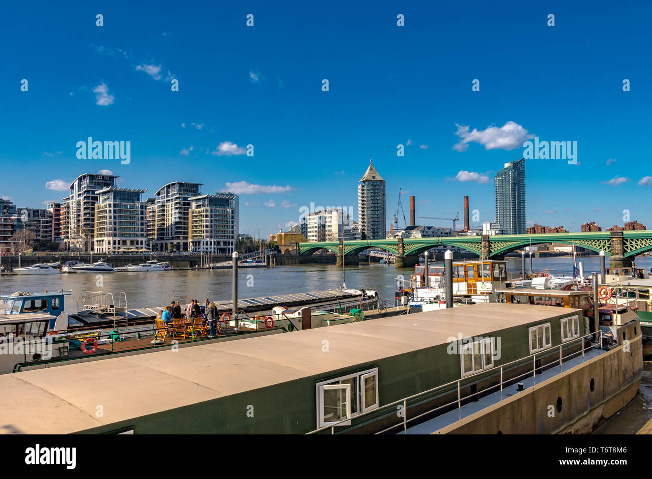 People sitting at a table on top of a houseboat  on The River Thames at  Battersea ,London, UK Stock Photo