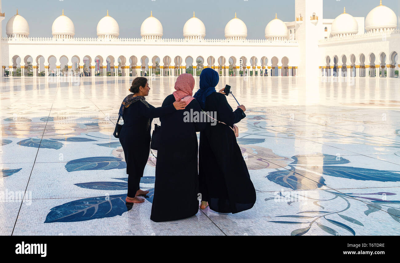 28 Dec 2017 - Abu Dhabi, United Emirates. Picture of a three muslim women taking selfies at beautiful Sheikh Zayed mosque. Stock Photo