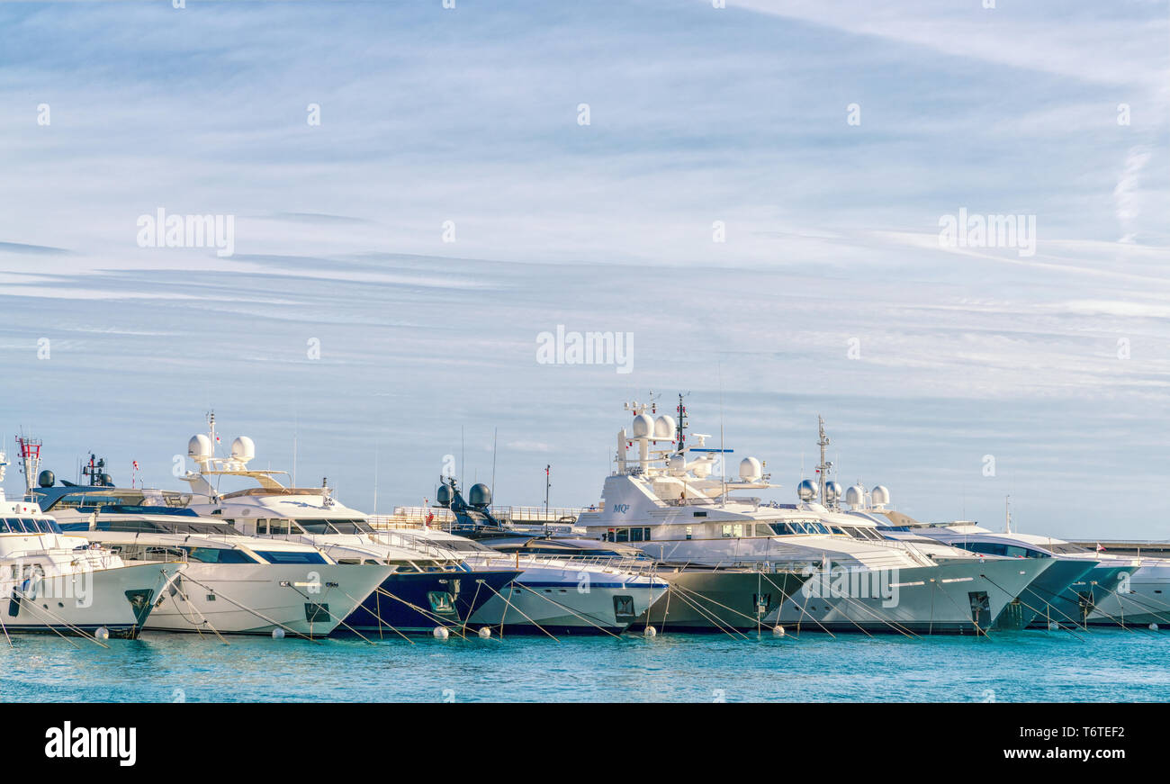 3 Nov 2018 - Monaco.  A row of modern, luxury boats neatly docked in the port. Blue sky in the background. Stock Photo